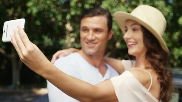 Couple taking a selfie on mobile phone near car alt