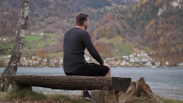 Sporty people take a break on a bench by a mountain lake - talk to each other and finish their break alt