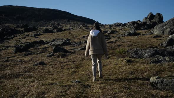 Young Girl in Beige Jacket Walks Among the High Mountains
