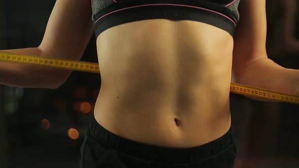 Sexy Woman Demonstrating Her Flat Belly and Fit Body, Measuring Waist With Tape alt