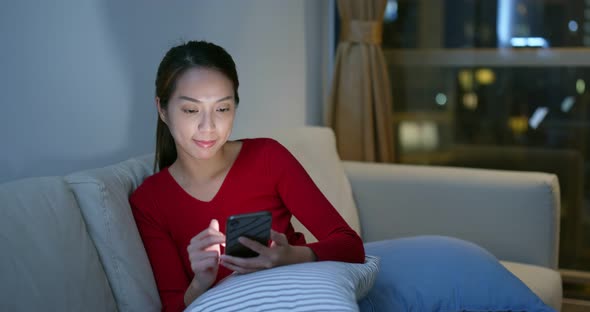 Woman use of mobile phone at home in the evening alt
