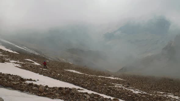 Tourist backpacker in the clouds descending from the mountain, High Atlas, Morocco alt