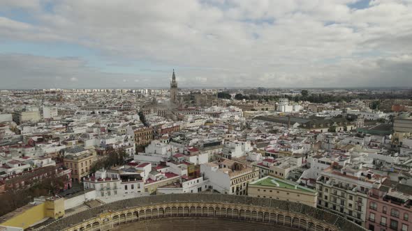 Drone flying over Plaza de Toros or bullring and Seville Cathedral in background, Spain.