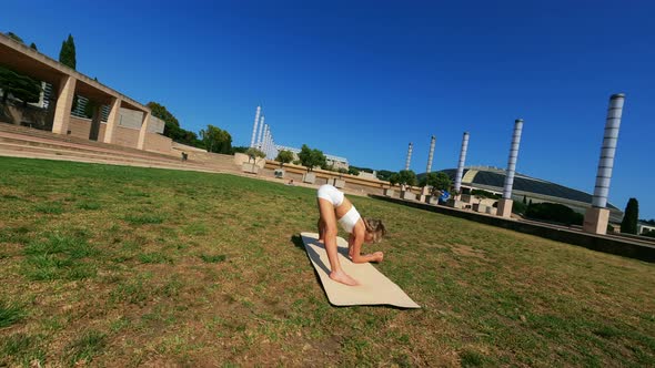 Girl in White Dress Doing Stretching Exercises on the Grass at Sunny Day