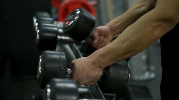 Man Hands Take Dumbbells From Gym Stand alt