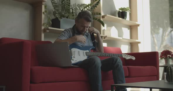 Bearded Man Finish Playing on Electric Guitar with Laptop and Headphones and Leave