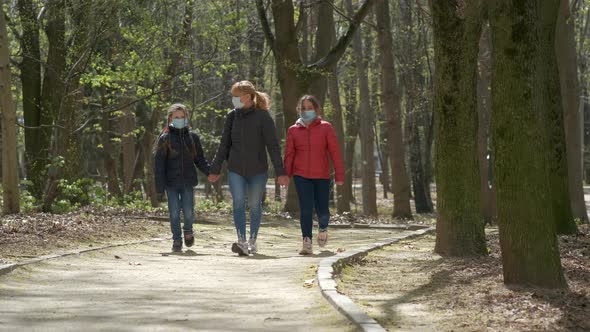A mother and two daughters walk in a spring Park in medical masks