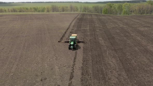 Tractor plows and cultivates the land for sowing alt