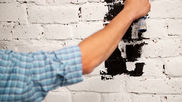 Footage Hand Painting a White Brick Wall with a Nice Dark Paint Roller