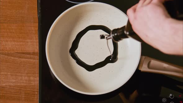 Male Hands Pour Black Oil on a White Frying Pan