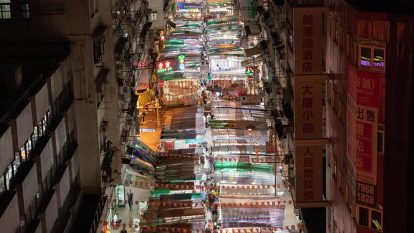 Time lapse of crowd of people walking at retail shops at night market in Monkok, Hong Kong. alt