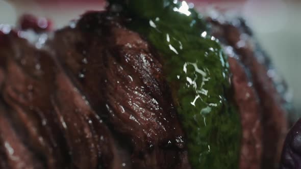 Close-up of Juicy beef steak filet mignon on plate is poured green herb sauce alt