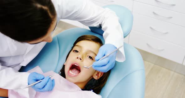 Dentist examining a young patient with tools alt