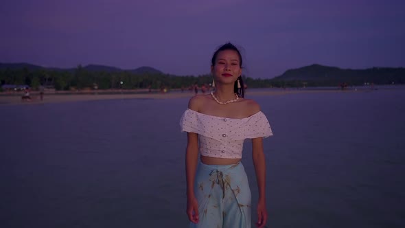 Young Asian Woman Walking on the Sea at Sunset Thailand