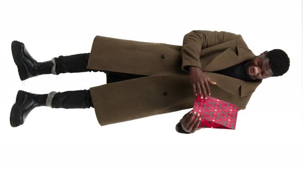 Bearded AfroAmerican Man Points at Red Gift Package and Shows It to the Camera Vertical Video alt