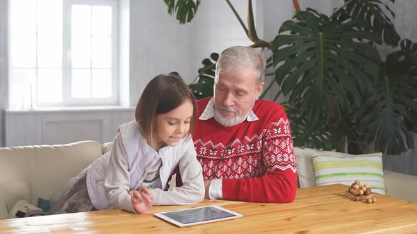 Happy Grandfather Playing Games with His Granddaughter Indoors alt