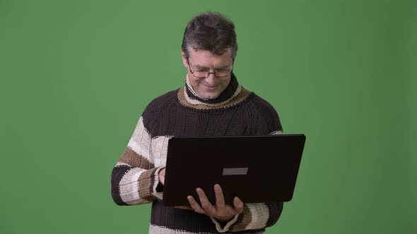 Mature Handsome Man Wearing Turtleneck Sweater Against Green Background