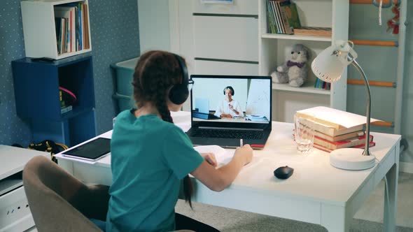 Teenage Girl Listening Closely To a Teacher During an Online Class alt