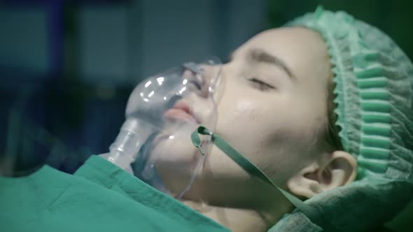 Close-up, a patient in an operating room who is using an oxygen mask to help them breathe.