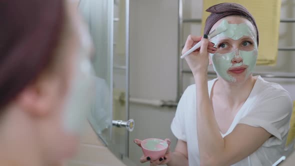 American Woman is Doing Cosmetic Procedure for Face While Standing in Home Bathroom Spbas alt