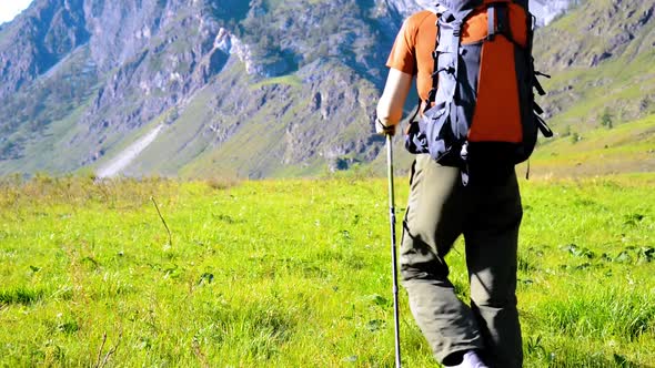 Hiking Man Walking on Green Mountain Meadow with Backpack alt