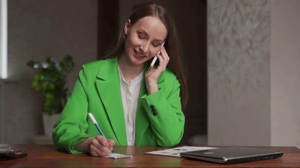Woman Talks to Client Via Mobile Phone Writing Notes alt
