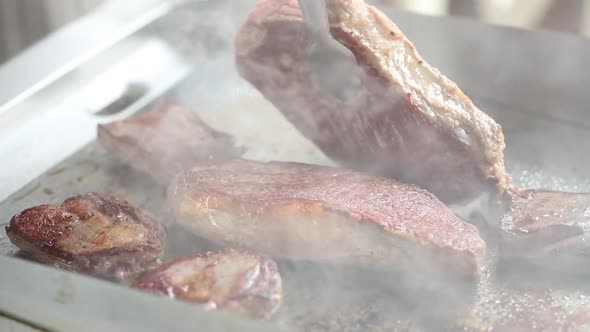 Cooking beef steaks on the stove with tongs. Close up video