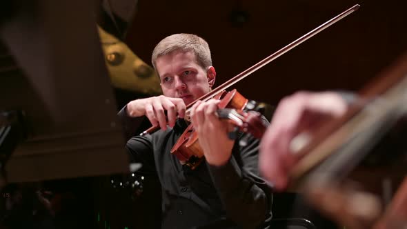 Young male violinist playing the violin to the accompaniment of the orchestra alt