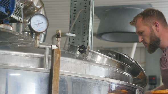 Beer Production. Man Adds Ingredients To Pot with Wort