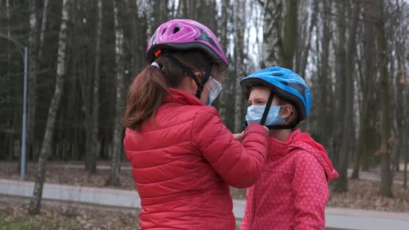 The older sister puts on a medical mask for the younger one before going for a bike ride