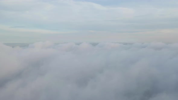 Aerial view of sunrise above fluffy sea fog misty clouds with mountain hill alt