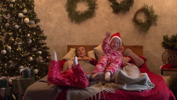 Family Having Fun and Cuddling on Bed on Christmas Morning