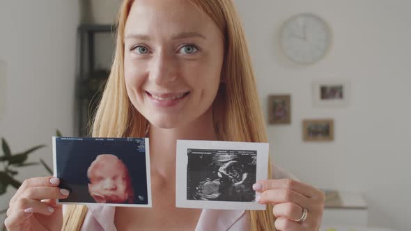 Portrait of Cheerful Expectant Mother with Prenatal Ultrasound Pictures alt