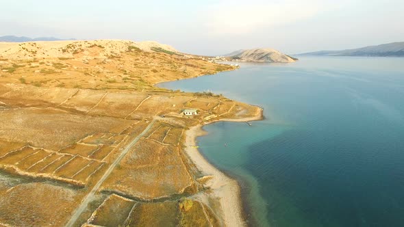 Flying above isolated house in yellow grass of Pag island at sunset, Croatia alt