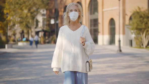 Middle Age Beautiful Woman Wearing Medical Mask Walking on Town Street alt