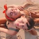 Young Caucasian Women Sunbathing Sits Leaning Back on Each on Sand Beach - VideoHive Item for Sale