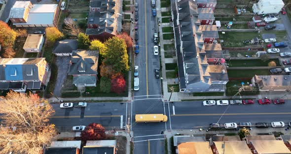 Tracking shot of yellow school bus driving through American urban city, residential community neighb alt