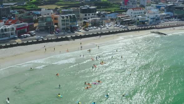 People who enjoy surfing on the blue beach overlooking Hallasan Mountain
