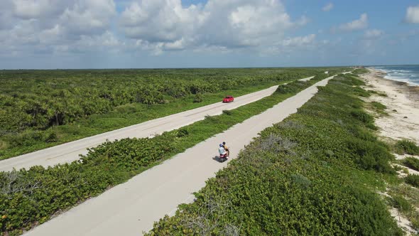 Tourists Riding Scooter Along Sea Shore