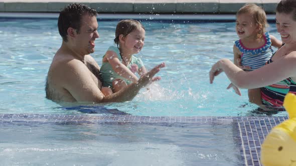 Family playing and splashing in backyard pool