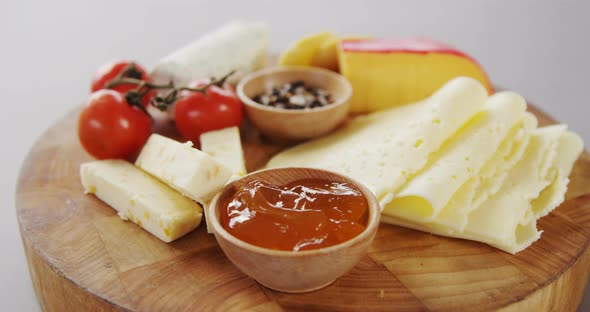 Different types of cheese, tomatoes and bowl of jam alt