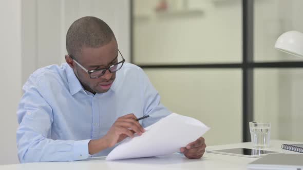 African Man Reading Papers at Work alt