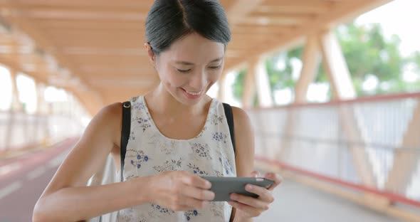 Woman playing game on mobile phone at outdoor  alt