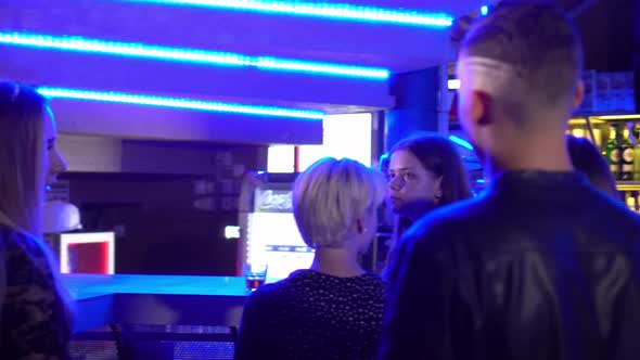 young girls are standing near the bar in a club talking, having fun, drinking alcohol alt