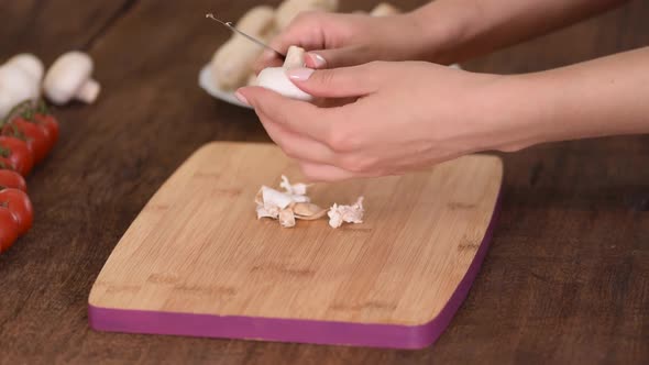  Woman is peeling off mushroom on kitchen. alt