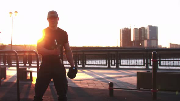 Young Sportive Man Training His Hands with Dumbbells on Sunset alt