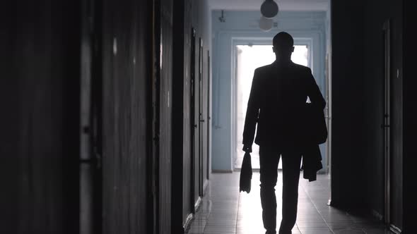 Silhouette of Businessman Walking in Corridor