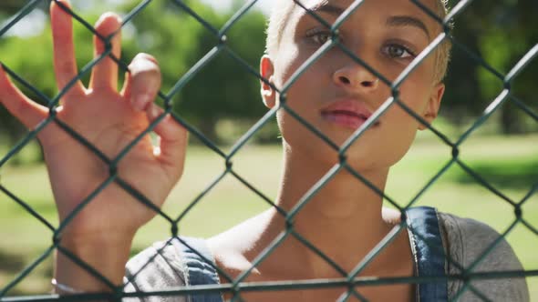 Mixed race woman looking through a fence alt