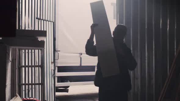 Man Carrying Plastic Block Into Hangar alt