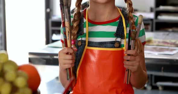 Portrait of cute schoolgirl standing with paintbrushes 4k alt